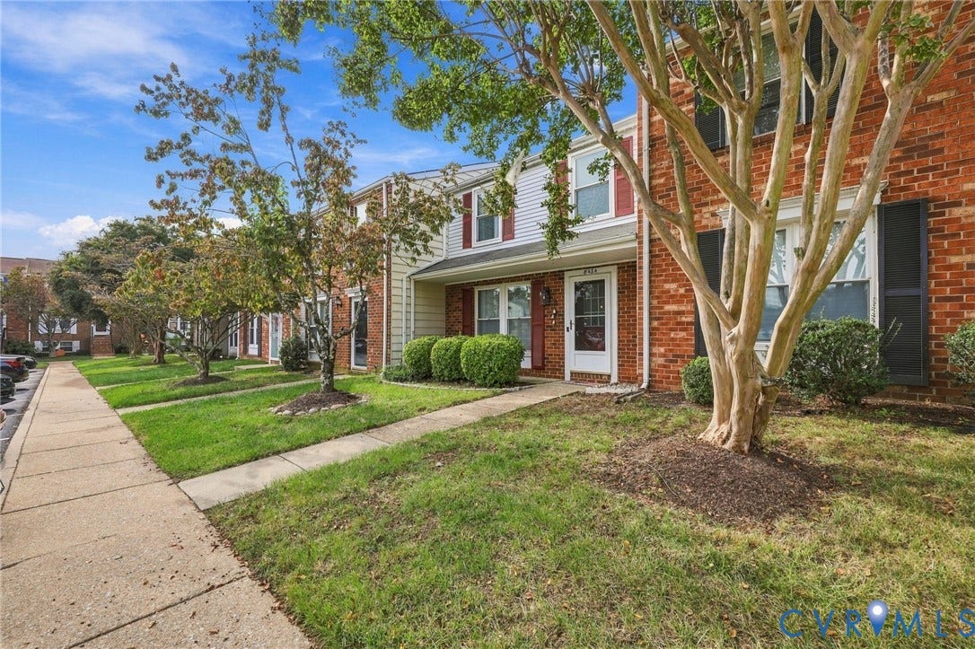 8434 Shannon Green Court, Henrico, VA 23228 Brick and siding facade with dark shutters, featuring a white entry door, concrete walkway, and landscaped front yard with established trees