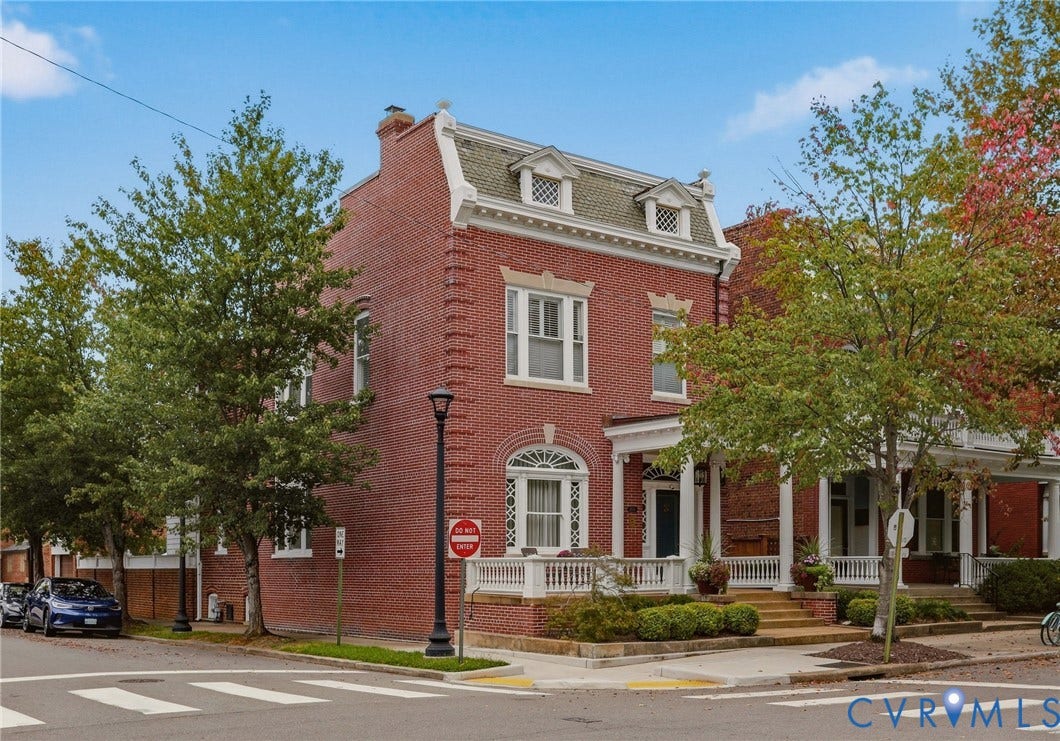 2624 Park Avenue, The Fan District, Richmond, VA 23220 Brick exterior featuring a mansard roof with dormer windows, a full-width porch with white railings, and a prominent arched window on the first level