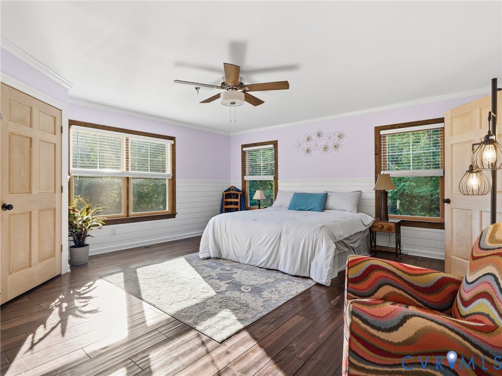 16233 Pleasant Mill Road, Montpelier, VA 23192 Room featuring dark wood-finish flooring, light-toned wood-finish panel doors, white wainscoting, multiple windows with dark wood trim, and a ceiling fan with integrated lighting
