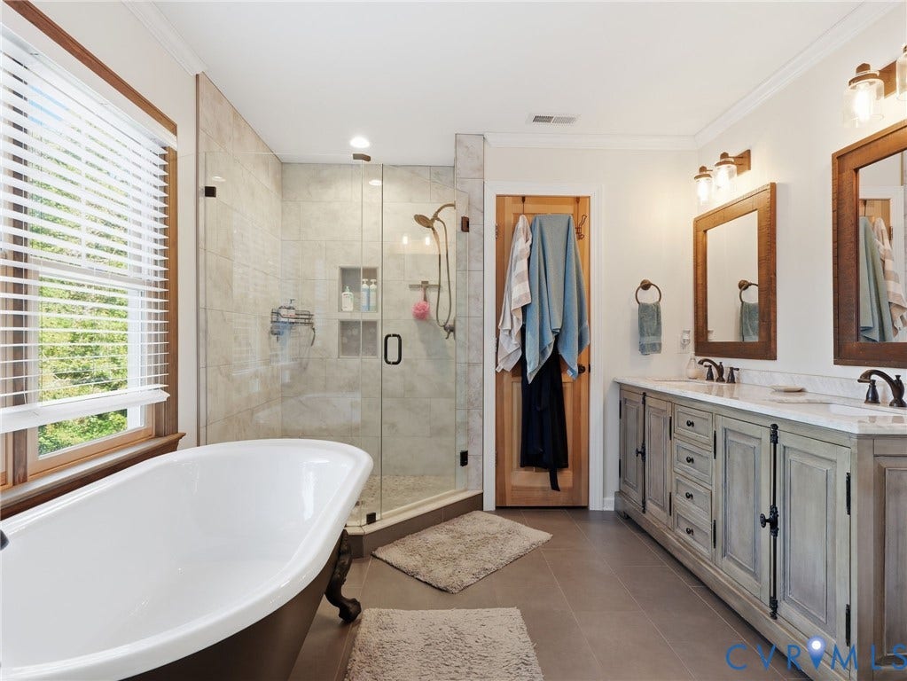 16233 Pleasant Mill Road, Montpelier, VA 23192 Freestanding soaking tub, glass-enclosed shower with tiled surround, double-sink vanity with stone countertop, and wood-framed vanity mirrors