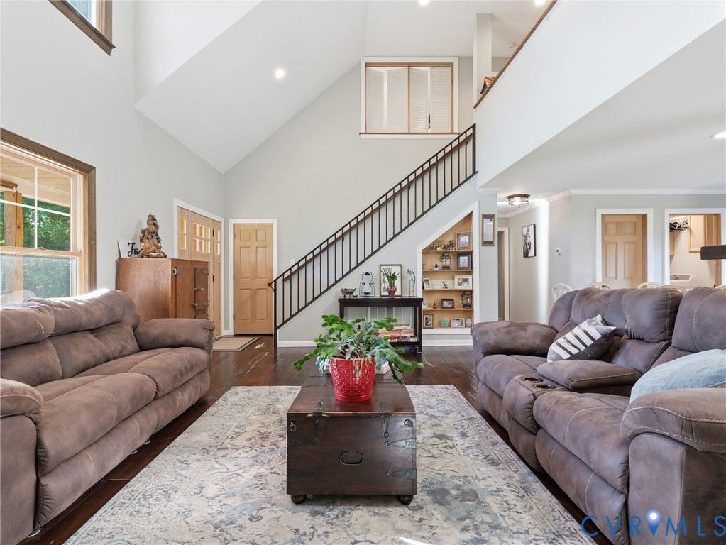 16233 Pleasant Mill Road, Montpelier, VA 23192 Vaulted ceilings, wood-finish flooring, metal staircase railing, built-in recessed shelving, and large windows with natural wood trim