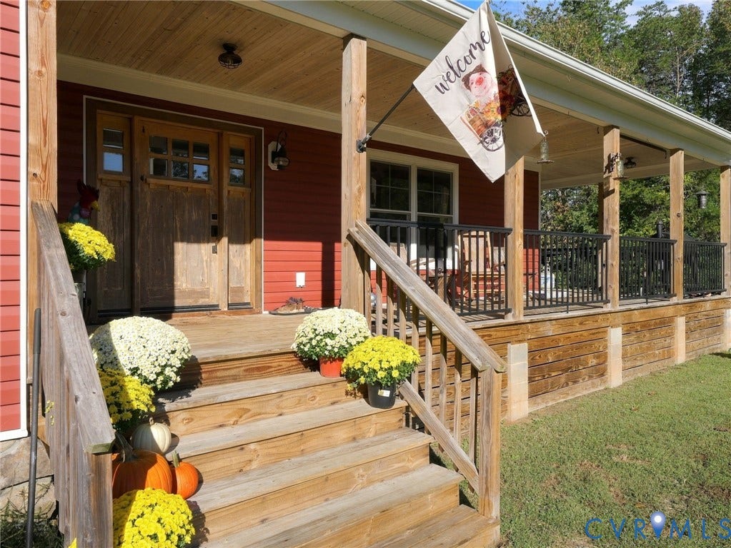16233 Pleasant Mill Road, Montpelier, VA 23192 Covered wooden front porch featuring horizontal lap siding, a wood-paneled ceiling, black metal railing, and a wood-frame entry door with multi-pane glass inserts