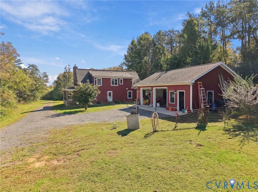 16233 Pleasant Mill Road, Montpelier, VA 23192 Two-story residence with red siding, detached multi-bay garage, stone-finish driveway, and expansive lawn area