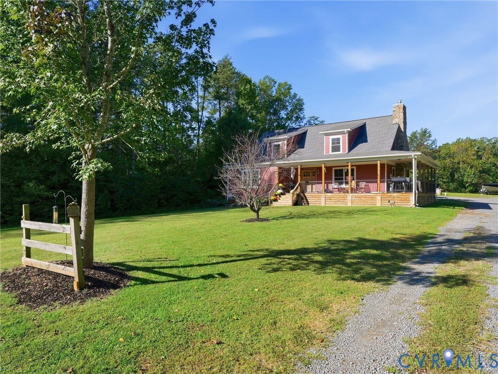 16233 Pleasant Mill Road, Montpelier, VA 23192 Two-story home with a wrap-around porch, stone chimney, wood-paneled exterior, asphalt shingle roof, and expansive front lawn