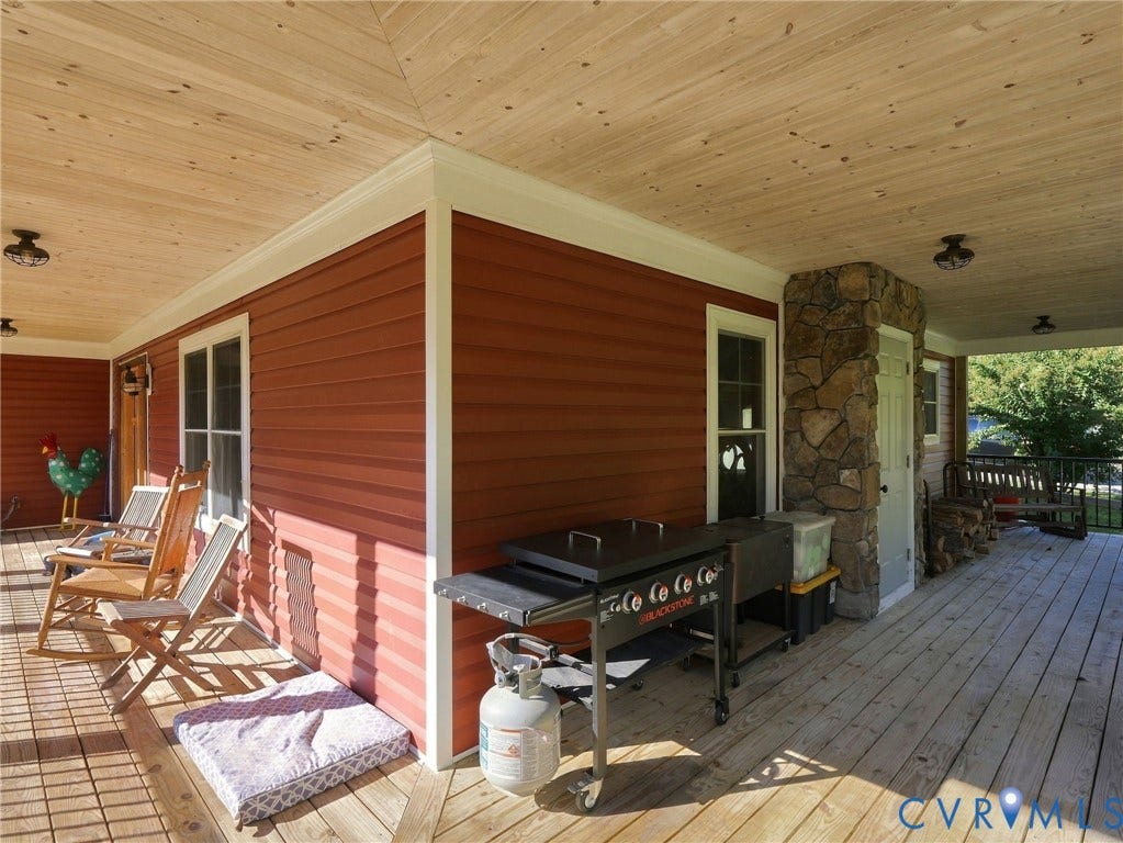 16233 Pleasant Mill Road, Montpelier, VA 23192 Wrap-around porch featuring wood-finish decking, natural wood-paneled ceiling, stone veneer pillar, and exterior lighting fixtures