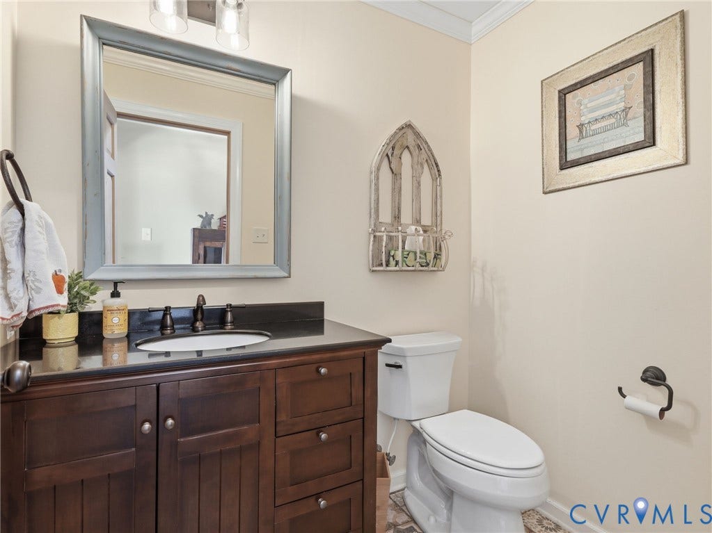 16233 Pleasant Mill Road, Montpelier, VA 23192 Dark-stained wood vanity featuring a stone countertop, an undermount sink with a widespread oil-rubbed bronze faucet, and a dual-light wall sconce
