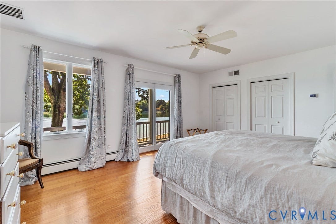 Hardwood flooring, white walls, multiple windows, double closet doors, and ceiling fan-balcony