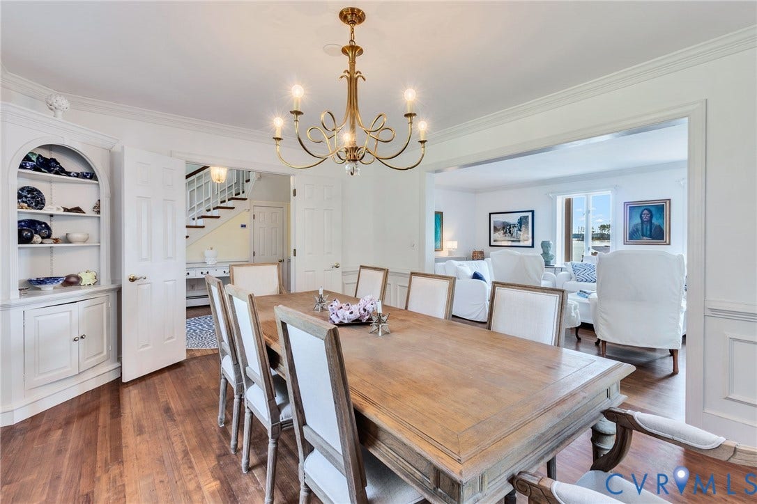 Hardwood flooring, custom built-in cabinetry, elegant chandelier, crown molding, and an expansive doorway