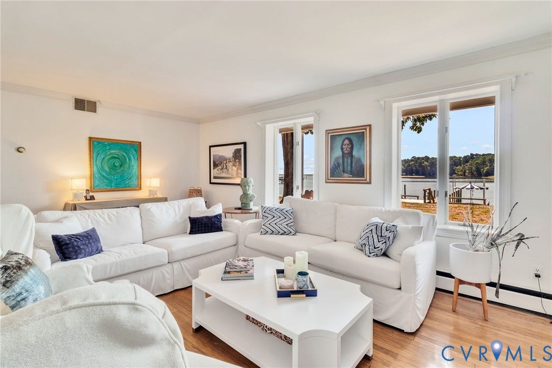 Hardwood flooring, white painted walls, crown molding, double windows, and water views
