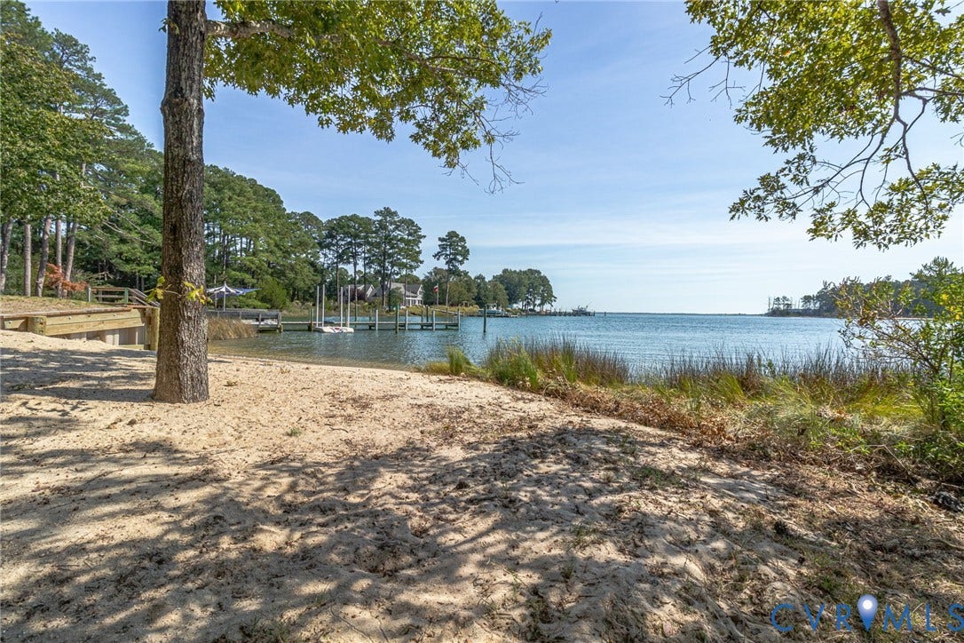Sandy beach area with mature trees, dock, and a prominent waterfront