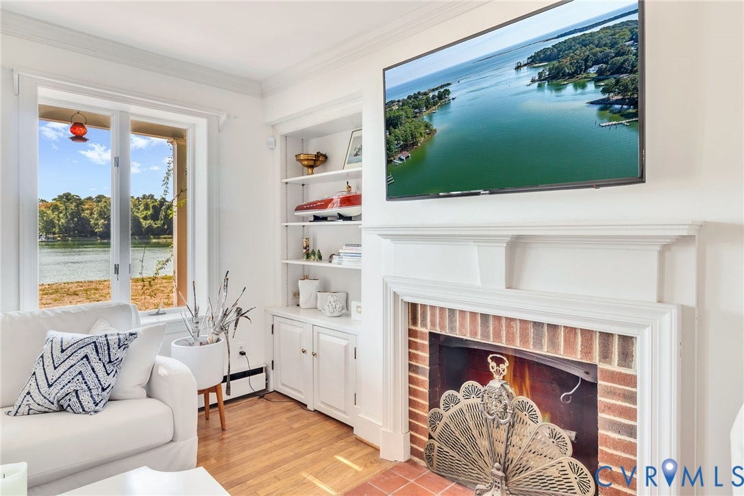 Waterfront window, wood-finish flooring, white built-in shelving, white mantel, and a brick fireplace surround