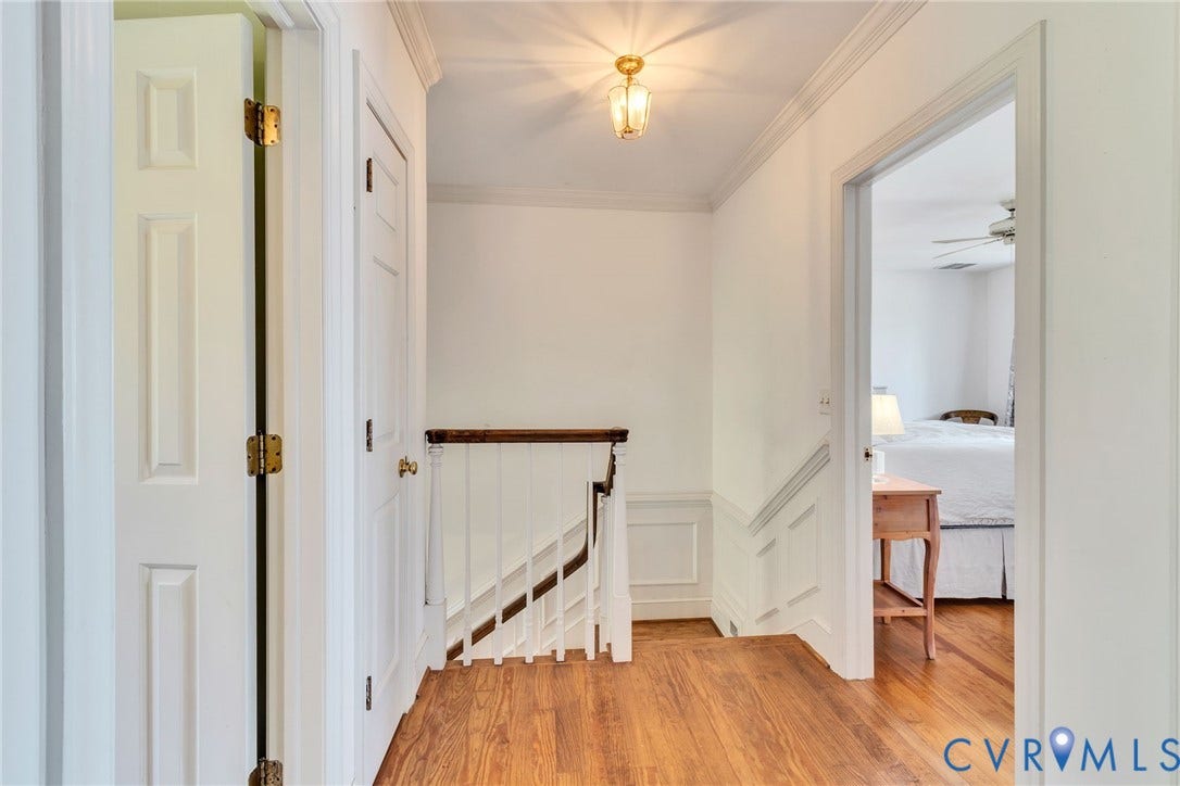 Stairs to second floor with white paneled wainscoting