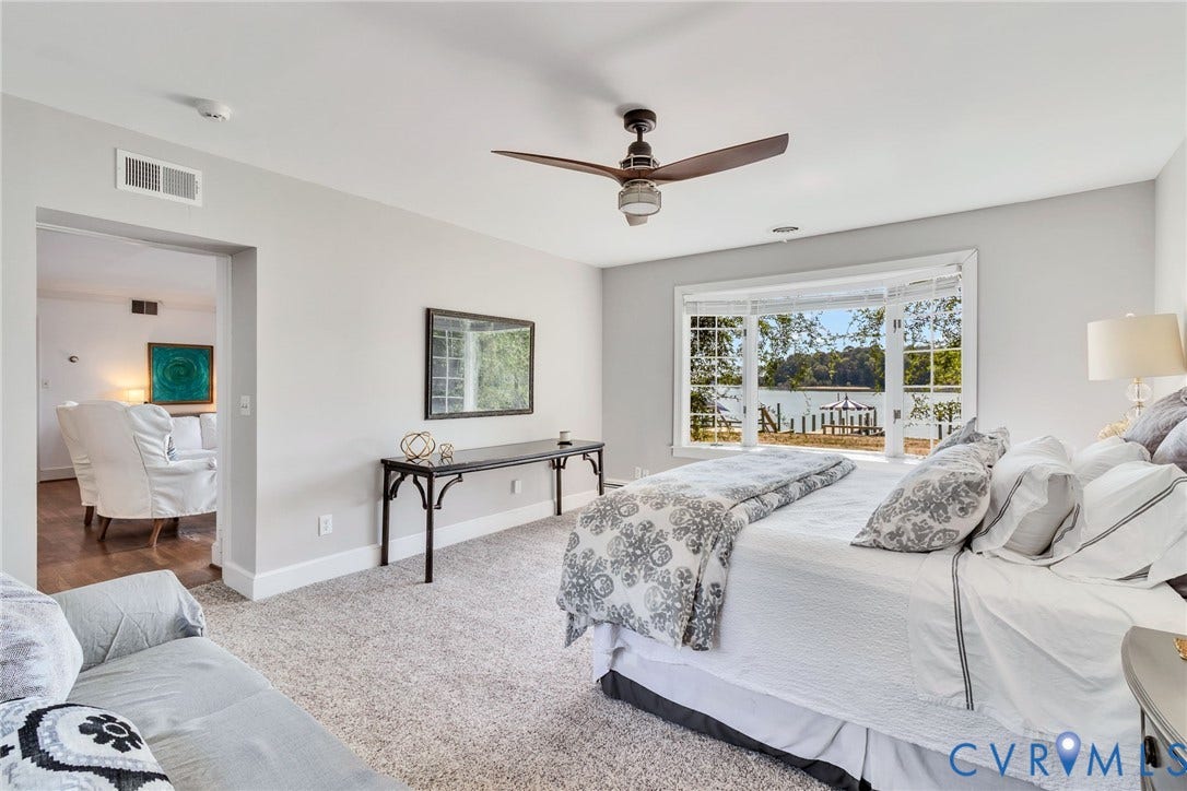 Light gray wall paint, textured carpeting, bay window with views out to the creek