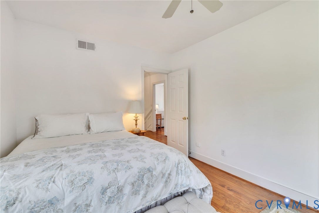 Hardwood-style flooring throughout, featuring a ceiling fan and white paneled interior doors