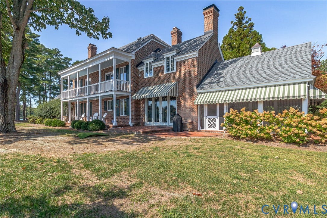 Brick exterior with multiple chimneys, covered porch, multiple French doors, and screened porch with striped awning