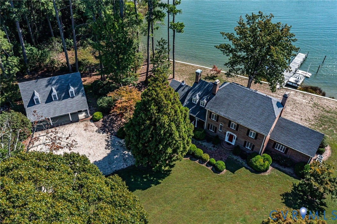 Main house with a private dock, waterfront access, lush green lawn, and a separate two-car garage building