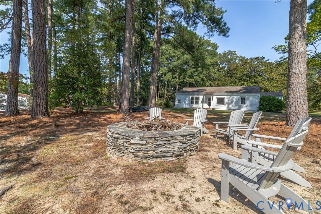 Backyard featuring a stone fire pit, mature trees, water views located between Main house and guest cottage