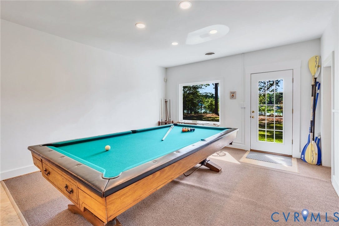Recreation room featuring carpet flooring, recessed lighting, a window with exterior scenery, and a glass-paneled door