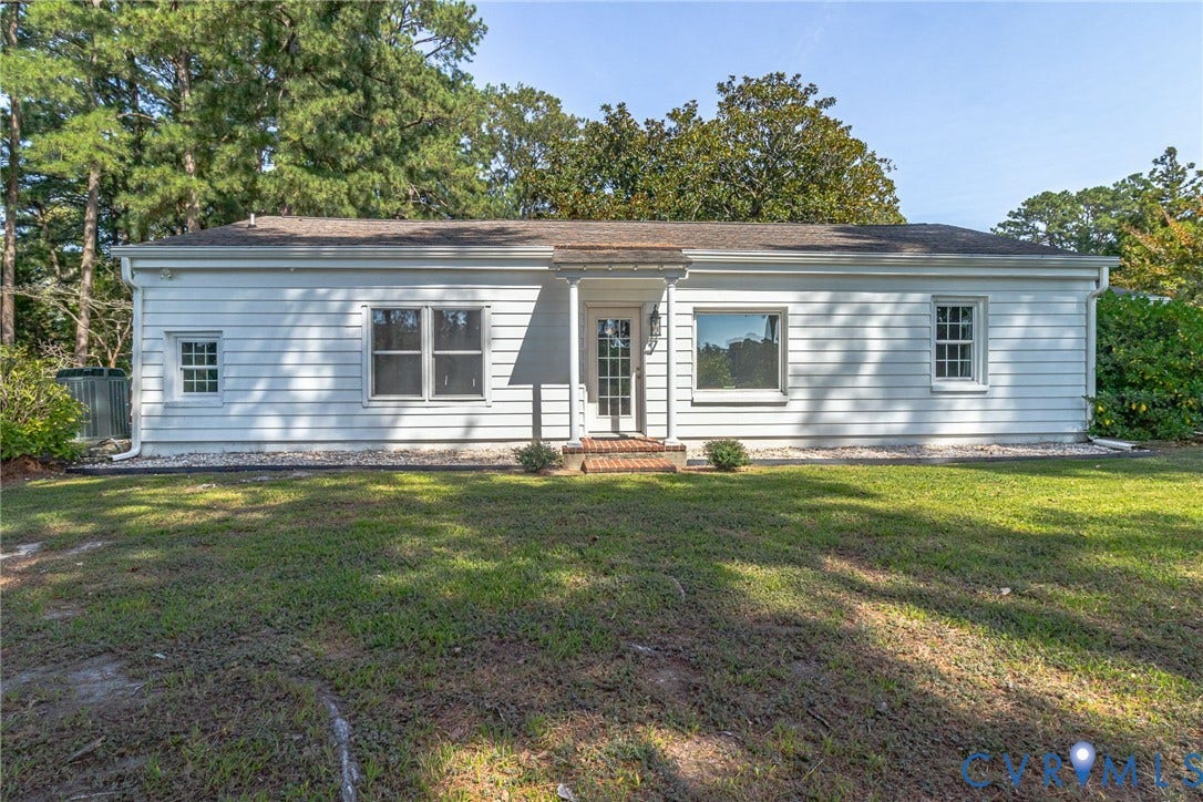 White siding exterior with multiple windows, a central entry door, and a gabled roofline
