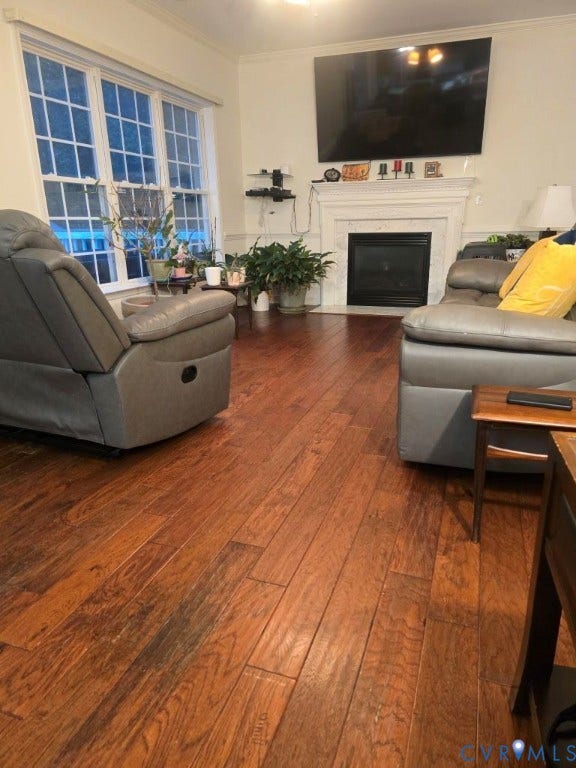 Hardwood-finish flooring, white trim, crown molding, double-hung windows, and a fireplace with a white mantel