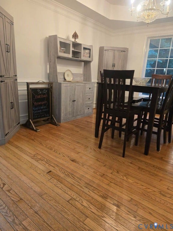 Hardwood flooring throughout, tray ceiling with chandelier, and built-in cabinetry with glass-front uppers