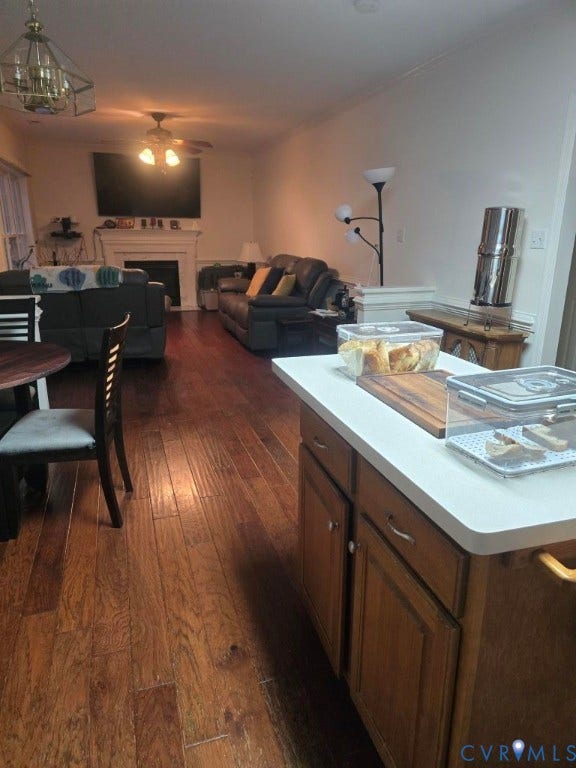 Wood-finish flooring throughout, with a built-in fireplace featuring a mantel, and a ceiling fan with integrated lighting