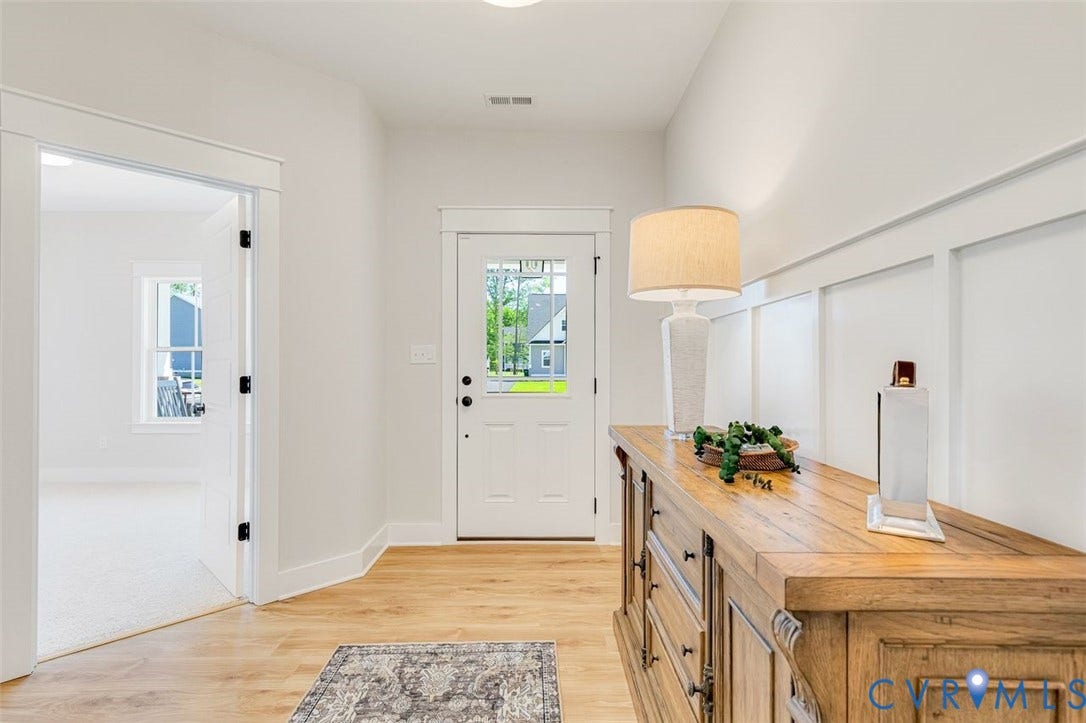 Recessed lighting, wood-finish flooring, white paneling, white trim, and a white front door with decorative glass inserts