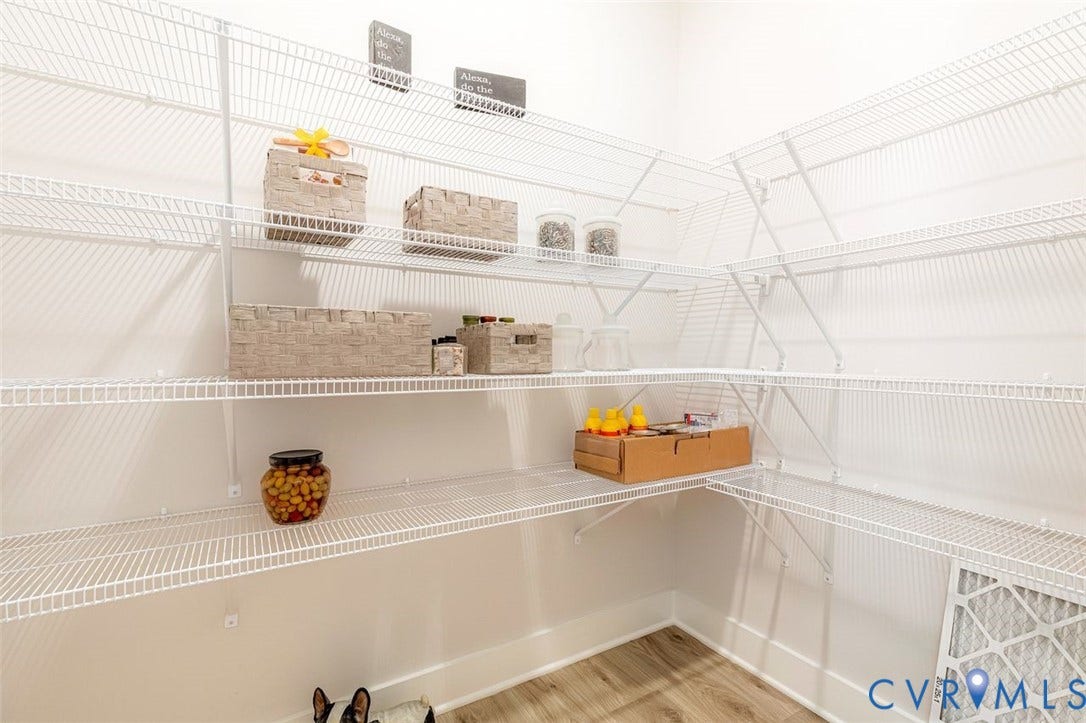 Walk-in pantry featuring white wire shelving, ample storage capacity, and wood-finish flooring