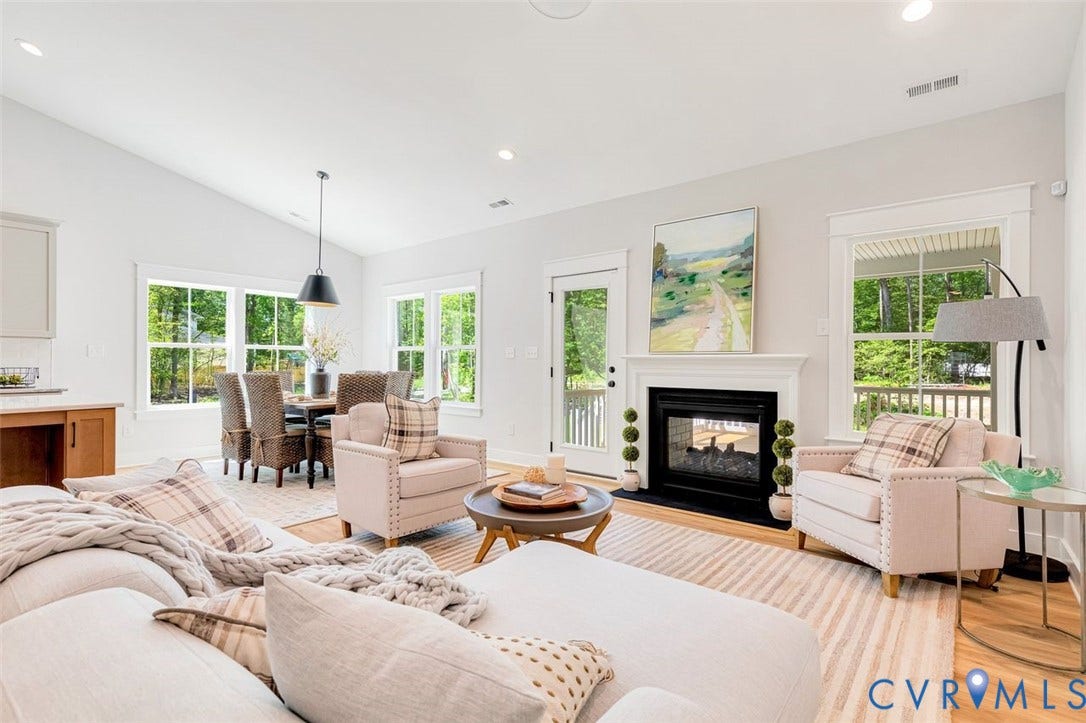 Vaulted ceiling with recessed lighting, fireplace with mantel, French door access to outdoor area, multiple large windows, and wood-finish flooring