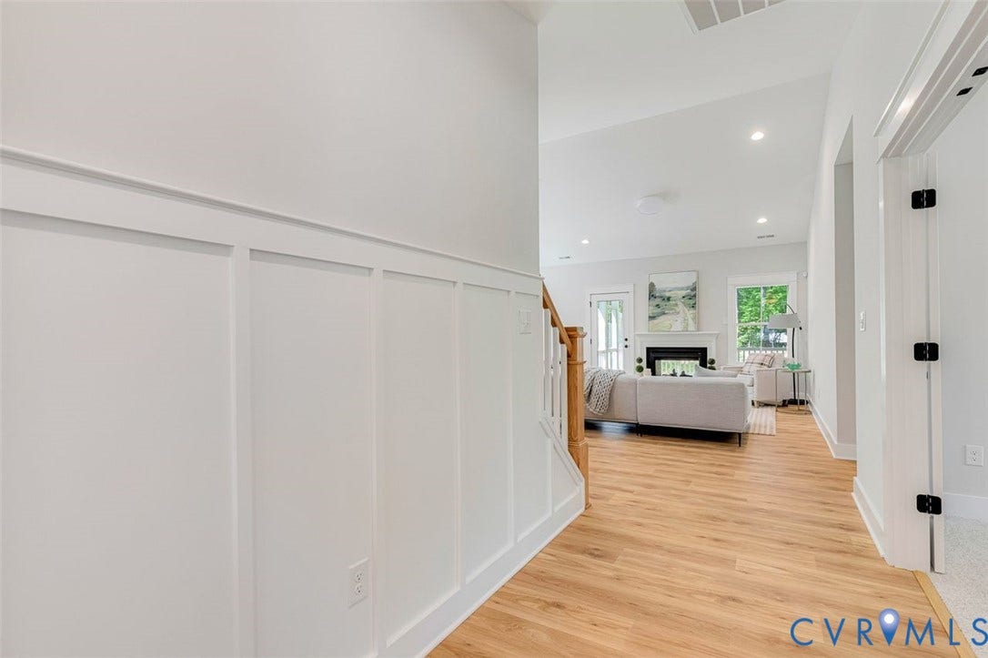 Board and batten wall detailing, wood-finish flooring, recessed lighting, vaulted ceiling, and a prominent fireplace