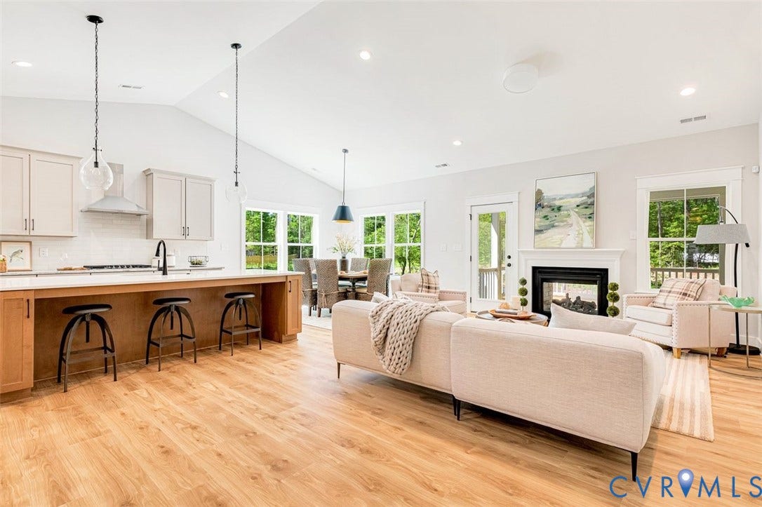 Vaulted ceilings with recessed lighting, wood-finish flooring, a kitchen island with built-in cabinetry, a fireplace with a mantel, and multiple windows