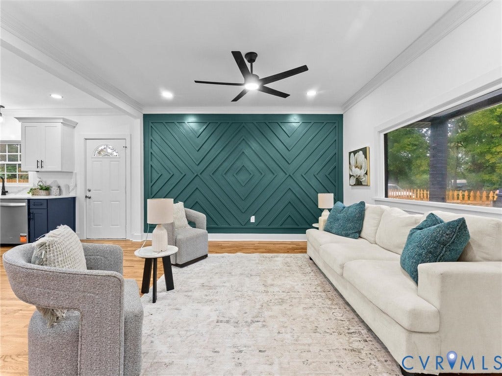 Hardwood-finish flooring, accent wall with geometric paneling, wide window, recessed lighting, and a ceiling fan with integrated lighting