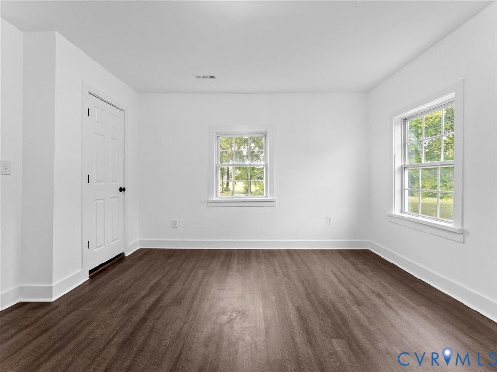Wood-finish flooring, white walls, and two windows with white trim