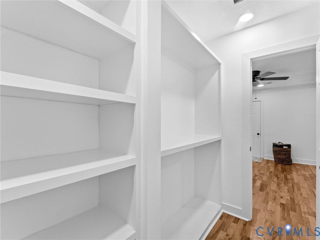 Built-in white shelving with recessed lighting and wood-finish flooring