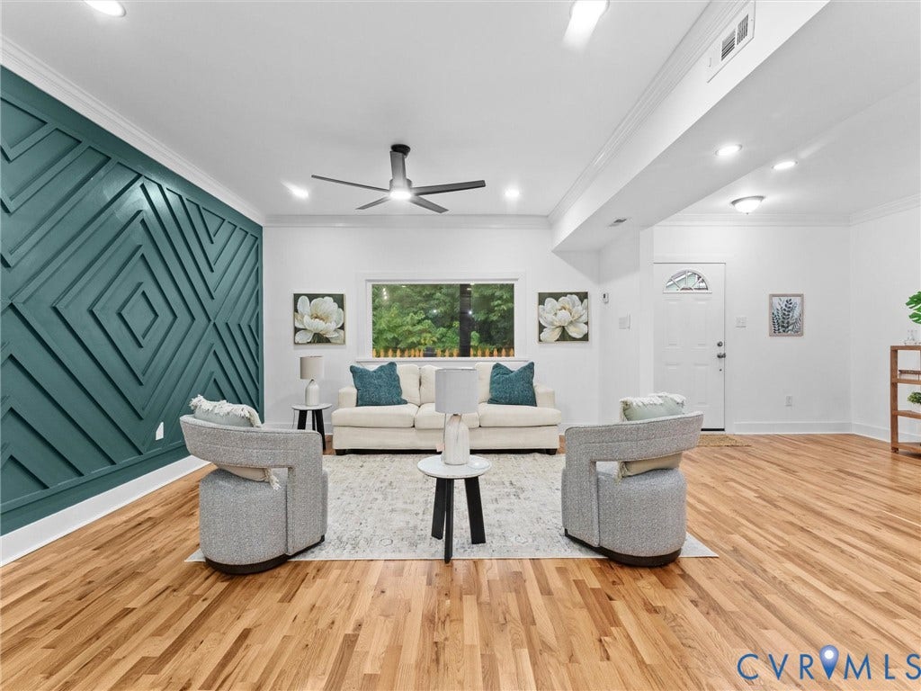 Hardwood-finish flooring, accent wall with geometric paneling, recessed lighting, ceiling fan, and white entry door with an arched window