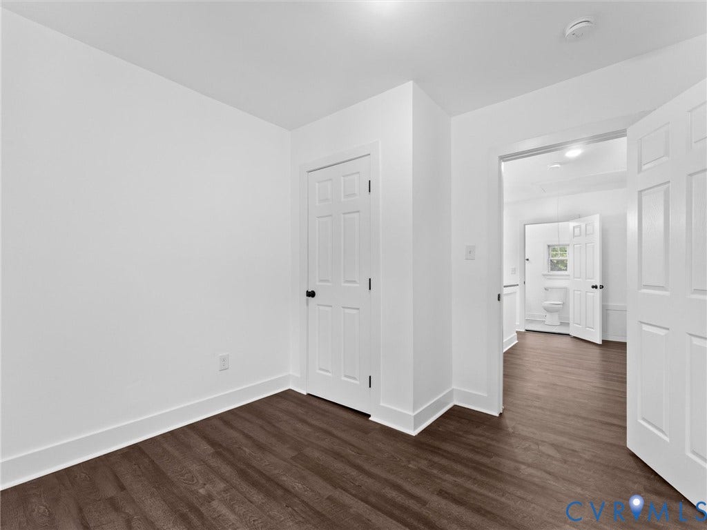 Dark wood-finish flooring, white trim, and white walls