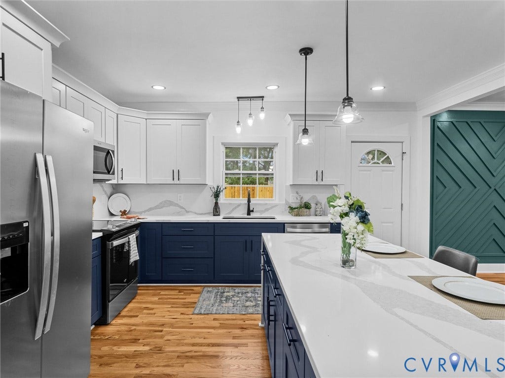Two-tone cabinetry with contrasting hardware, light wood-finish flooring, stainless steel appliances, white countertops with integrated sink, and recessed lighting