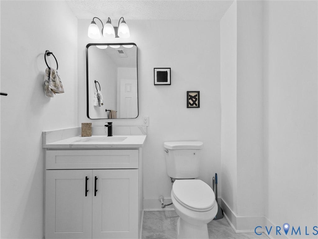 White vanity with integrated sink, black faucet, and cabinet storage