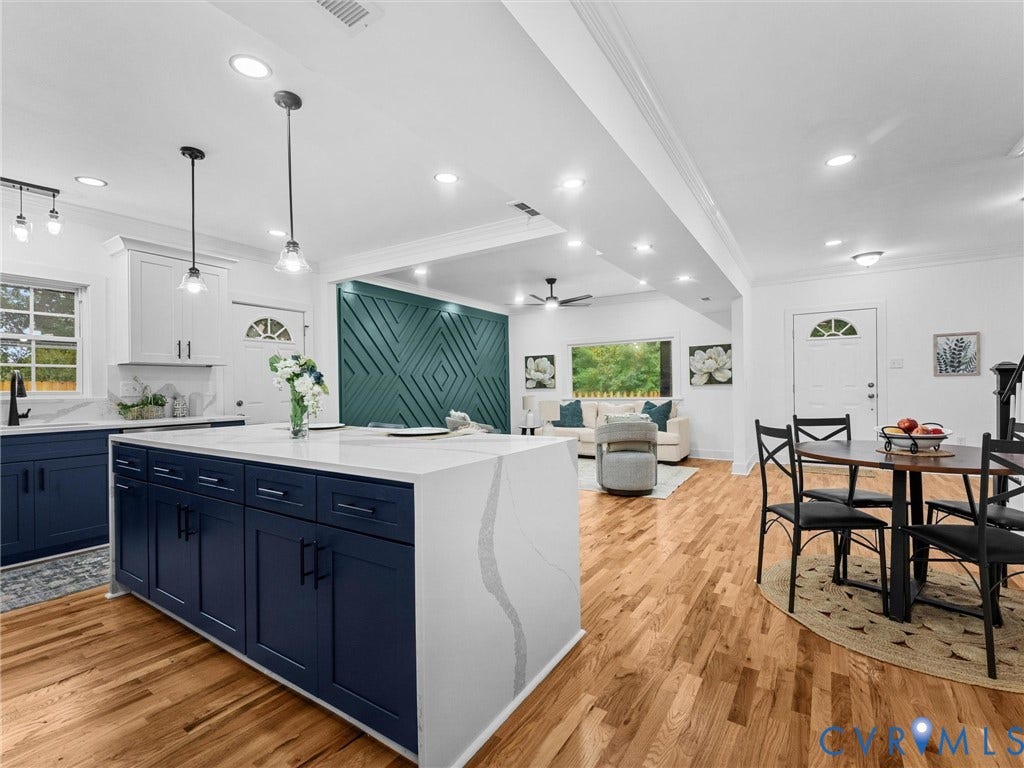 Open concept living area featuring wood-finish flooring, recessed lighting, and a kitchen island with a waterfall countertop