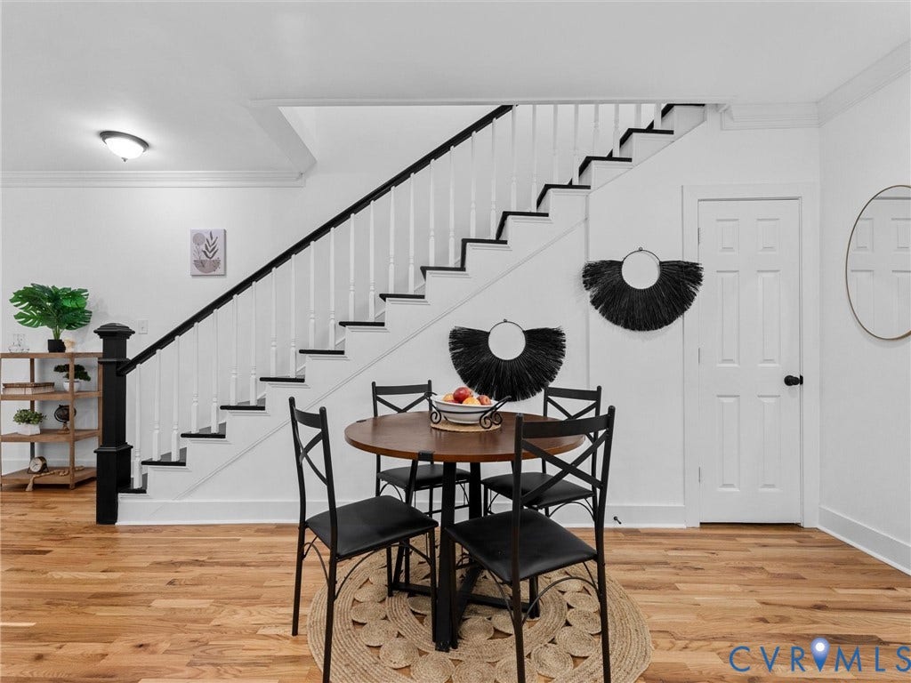 Hardwood flooring, two-tone staircase, interior door, ceiling light fixture, and white trim molding