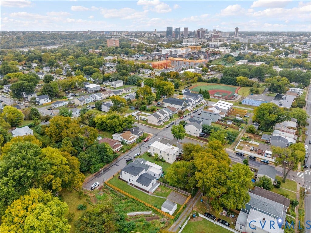 Urban setting with extensive tree canopy, residential streets, and a distant city skyline
