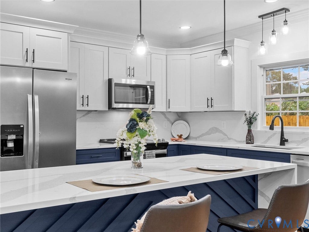 White upper cabinetry with contrasting blue lower cabinetry, stainless steel appliances, white countertops, and a modern black faucet