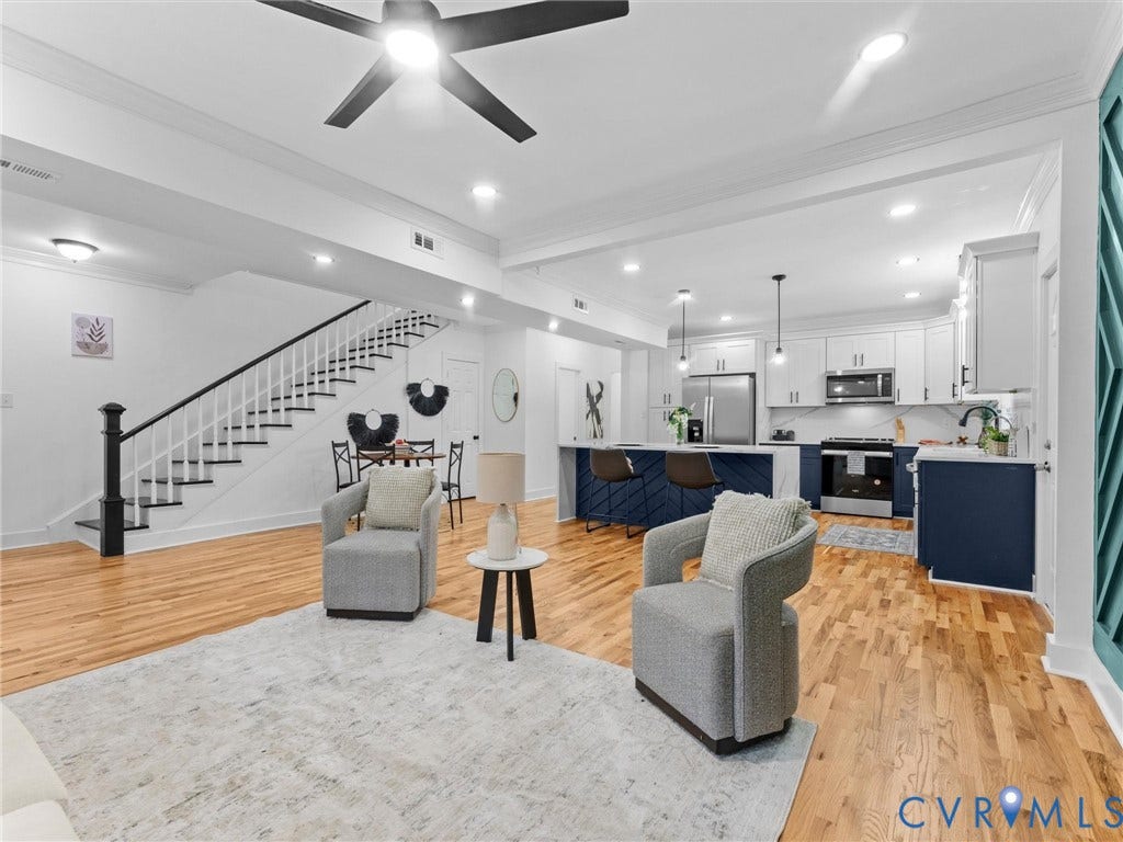 Open-concept living space featuring hardwood flooring, a modern kitchen with a two-tone island, stainless steel appliances, and recessed lighting