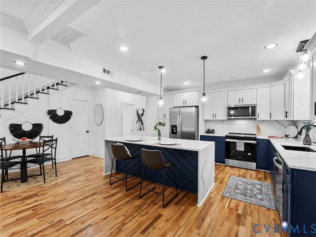 Kitchen with two-tone cabinetry, stainless steel appliances, and a central island with pendant lighting