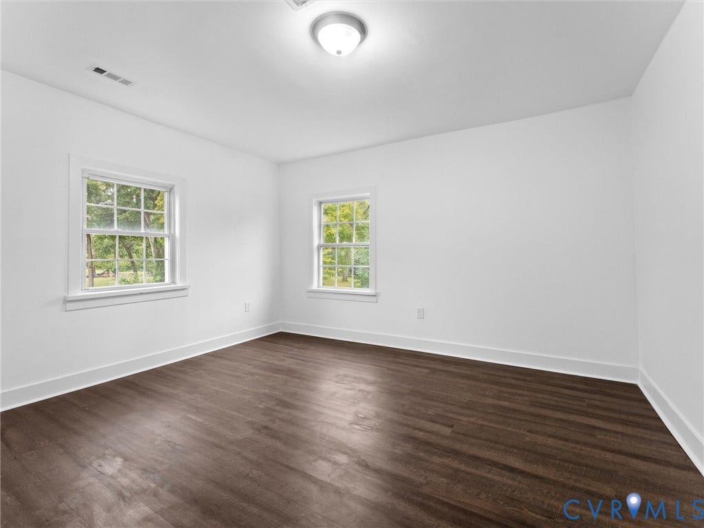 Dark wood-finish flooring, white walls, and two multi-pane windows