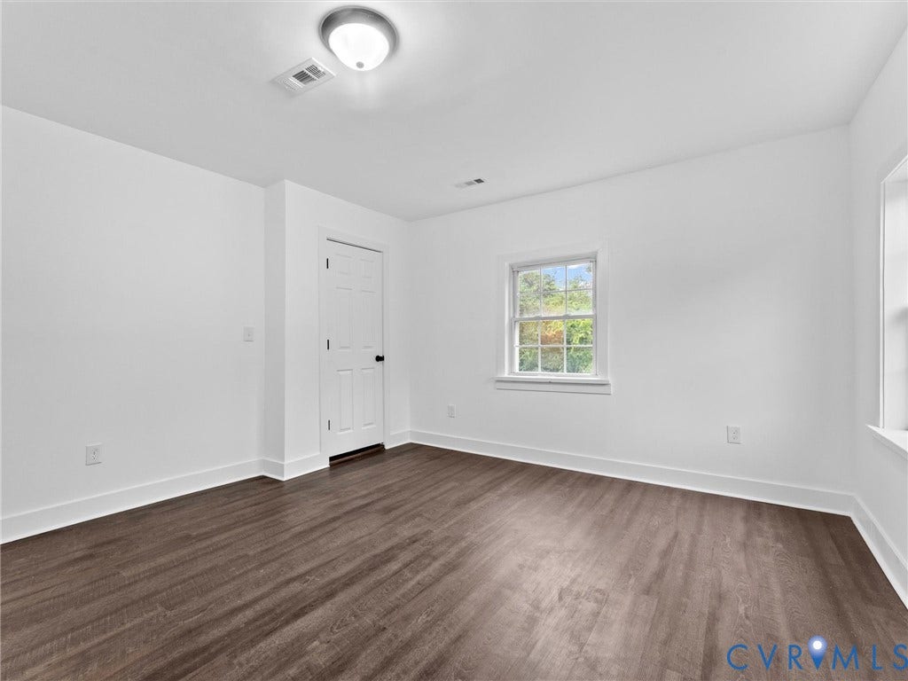 Neutral wall paint, wood-finish flooring, white trim, and a double-hung window