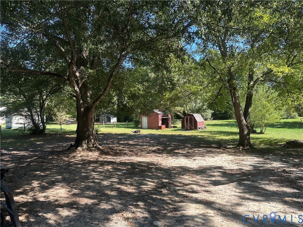 5539 Qualla Road, Chesterfield, VA 23832 Mature shade trees with lush foliage, two red storage sheds, and a substantial grassy area