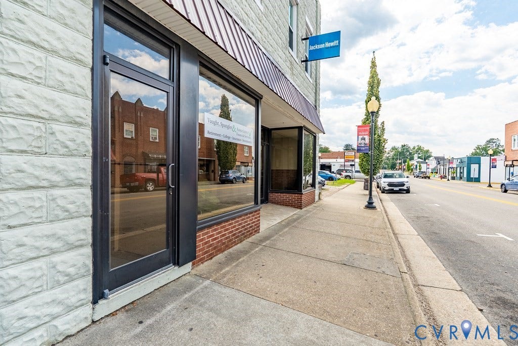 Stone block facade with a storefront entry, large display window, and a brick base