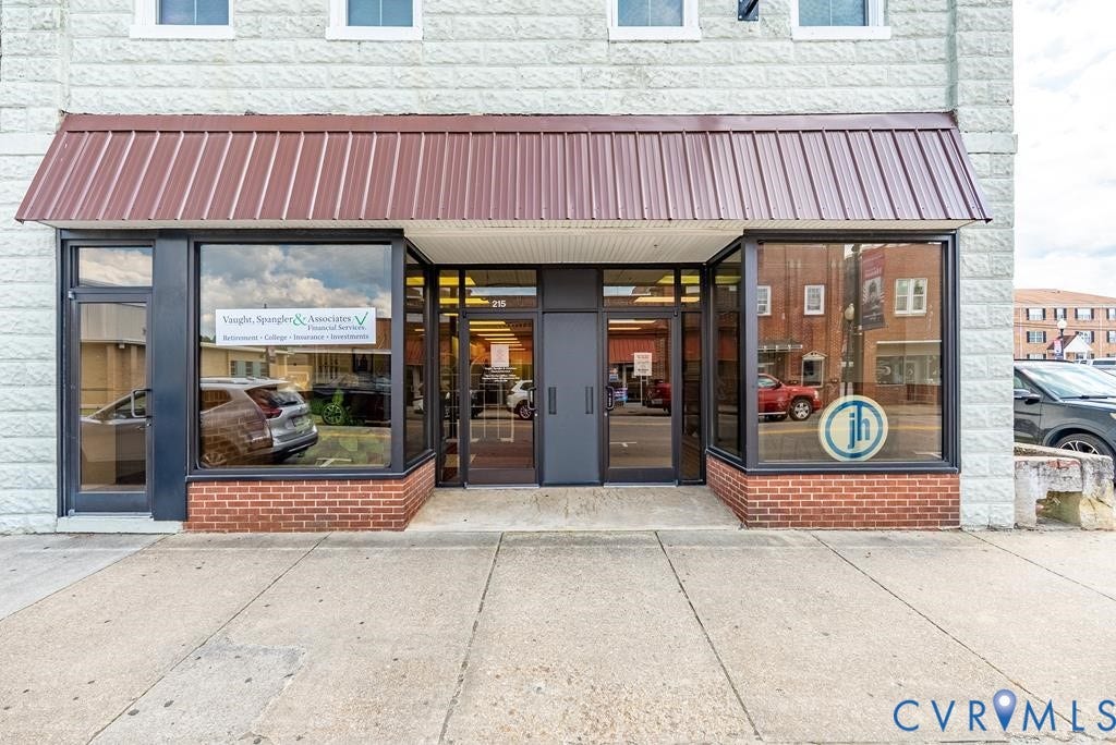 Brick-front facade with large display windows, a central entrance, and a metal awning