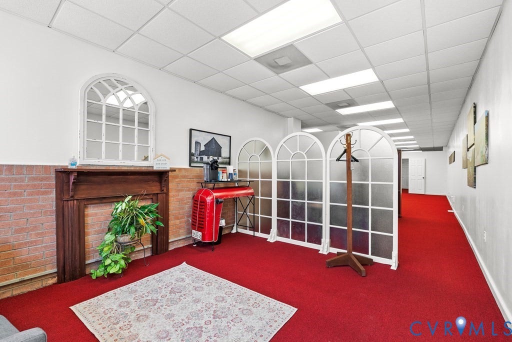 Red carpet flooring with a brick half-wall, wood-finish mantel, and arched decorative room dividers